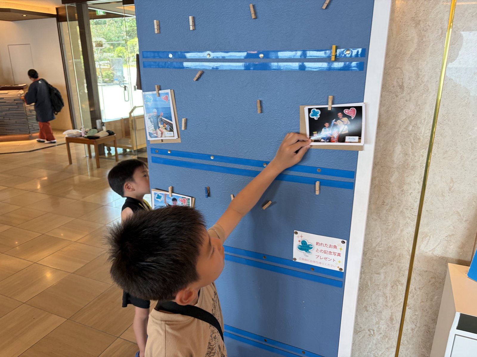 フロント前の掲示板から釣った魚との記念写真を取る子ども